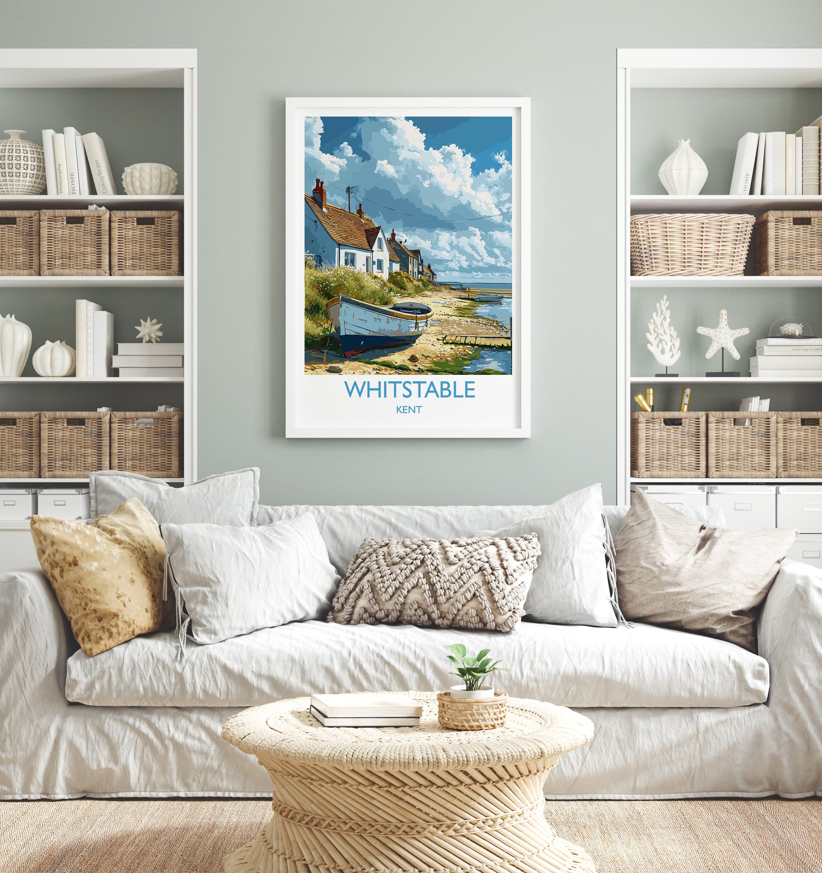 a living room with a white sofa, a coffee table, and a framed poster of a coastal village on the wall.