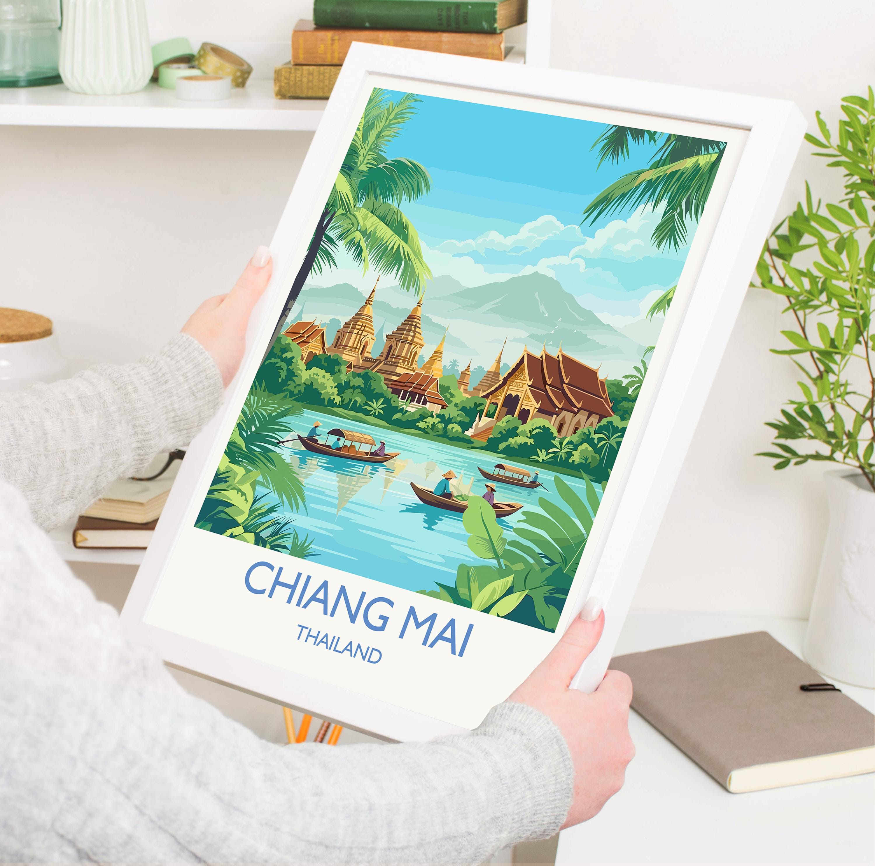 A person is holding a framed poster of a tropical landscape with boats on a river, surrounded by lush greenery and mountains.