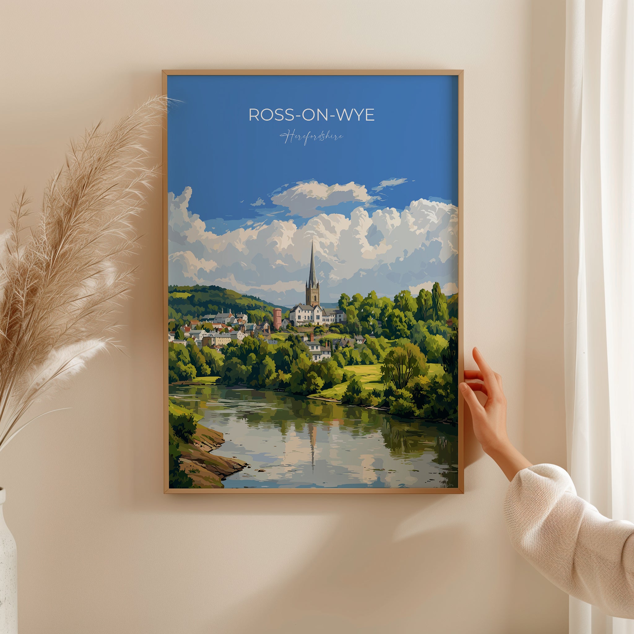 A framed painting of a picturesque town with a river and a church spire in the background, hanging on a wall.