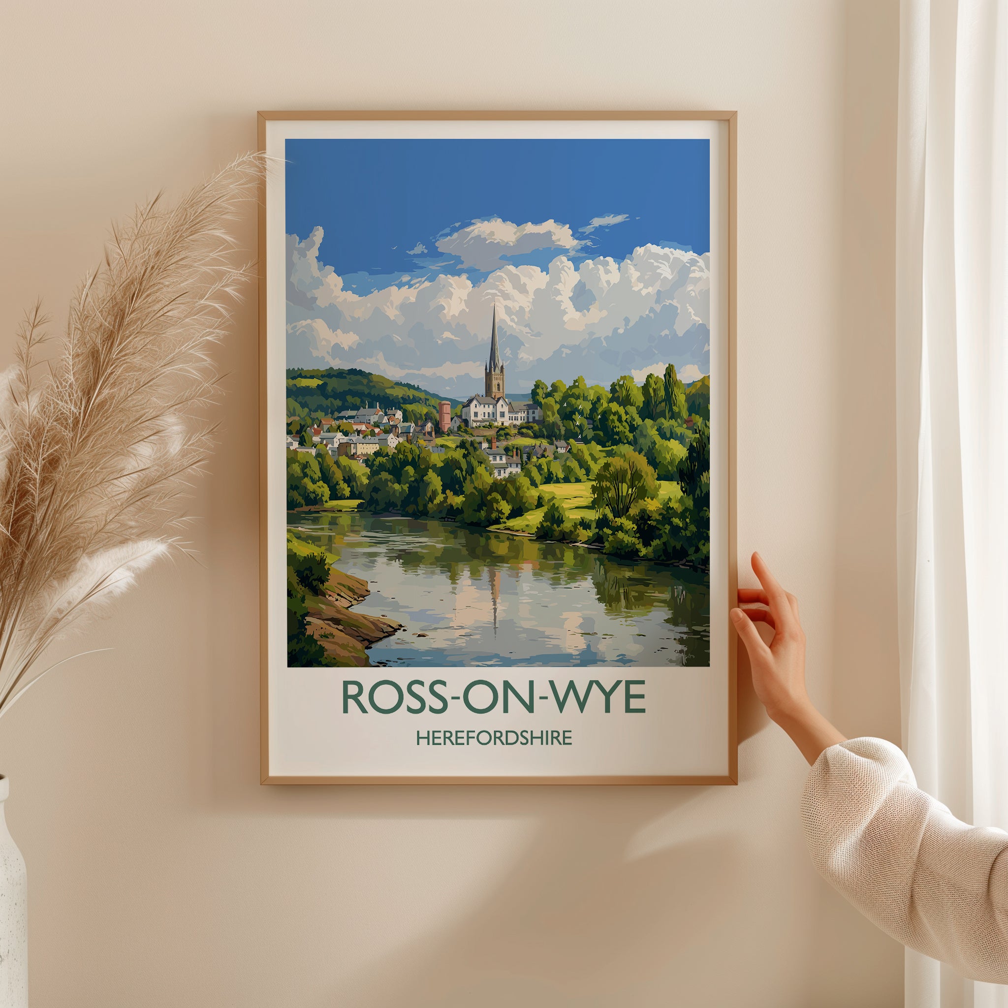 A framed poster of Ross-on-Wye, a picturesque town in Herefordshire, England, with a person's hand holding the frame against a wall.