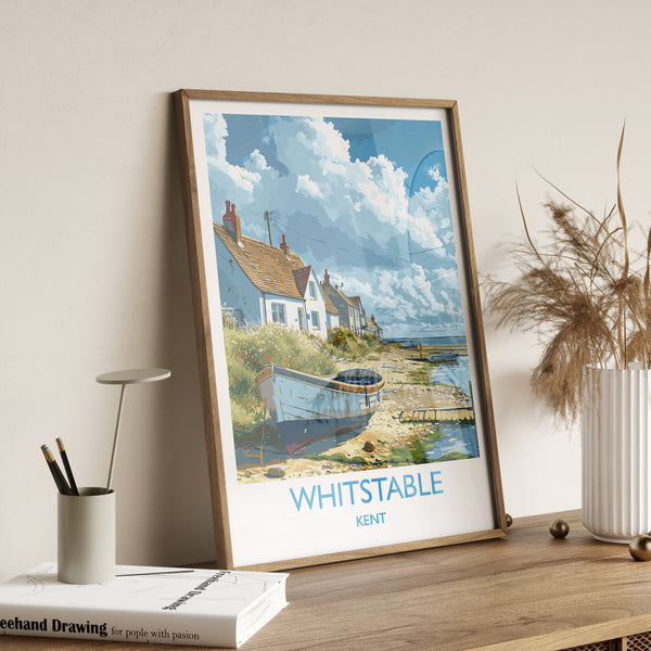 A framed poster of a coastal village in Kent, England, featuring a small boat on the shore and a cloudy sky in the background.