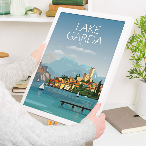 a person holding up a poster of lake garda