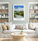 a living room with a white sofa, a coffee table, and a framed poster of a scenic view of Ross-on-Wye, a town in the Hebrides of Scotland.