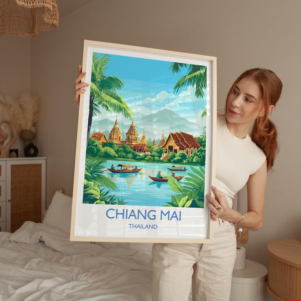 A woman is holding up a framed poster of a tropical landscape with boats and buildings, including a temple, in front of her.