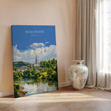 a large canvas print of a scenic landscape with a river, trees, and a church spire, displayed on a wall next to a vase.