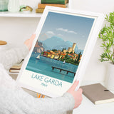 a person holding up a picture of lake garda